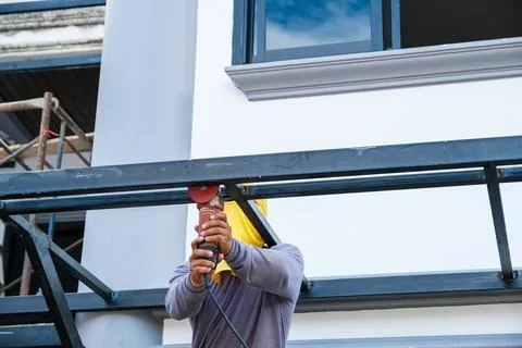 The contractor is using an electric grinder to decorate the steel welding point. Stock Photos