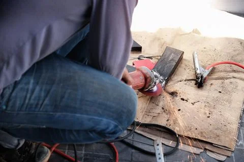 The contractor is using an electric grinder to decorate the steel welding point. Stock Photos