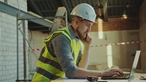 Contractor Using Laptop and Checking Floor Plans during Phone Conversation Video stock 273478132