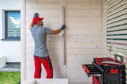 Contractor Using Level on Wooden Wall During Construction Stock Photos