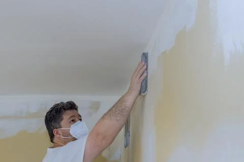 Contractor using sand trowel sanding the drywall Stock Photos