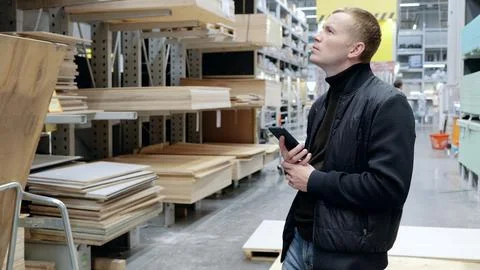 Contractor using a smartphone to select wood materials in a lumber warehouse for Stock Photos