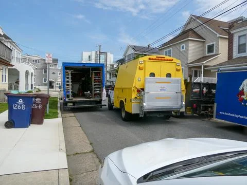 Contractor's work trucks blocking a small street in a residential area Stock Photos