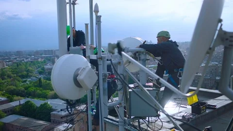Contractors, Workers servicing cellular antenna in front of city. The cell tower Stock Footage