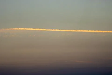 A contrail over clouds at sunset Stock Photos