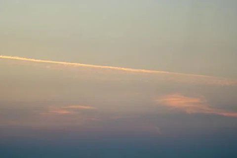A contrail over clouds at sunset Stock Photos