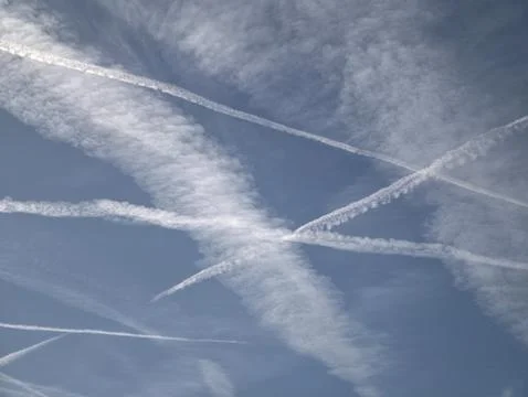 Contrails And Clouds In Open Blue Sky. Crisscrossed Vapor Streaks Under Exp.. Stock Photos