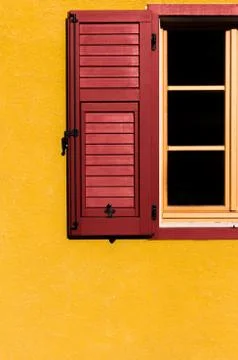 Contrast between red window open on yellow wall Stock Photos