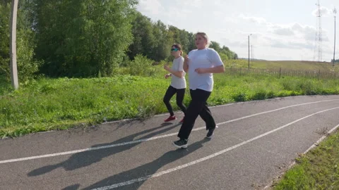 Contrast of plus-size and slim girls running on stadium track surrounded by Stock Footage 311582817