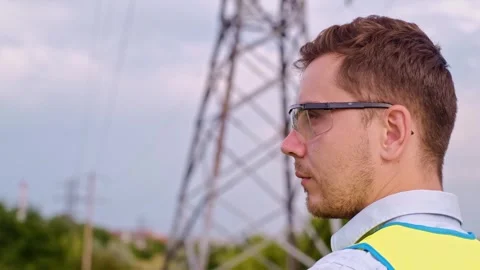 Control engineer with tablet pc, power lines and pylons, discussing expansion pl Vidéo 252667359