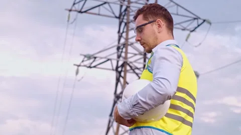Control engineer with tablet pc, power lines and pylons, discussing expansion pl Vidéo 252667367