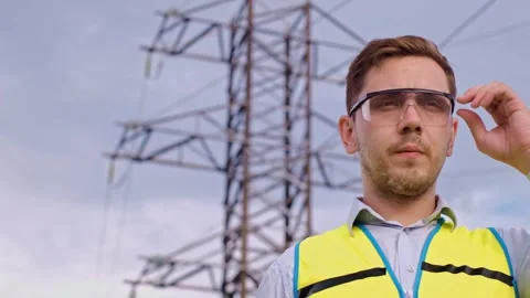 Control engineer with tablet pc, power lines and pylons, discussing expansion pl Stock Footage 252667368