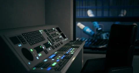 Control panel in an industrial setting with robotic machinery in background Ilustración de archivo