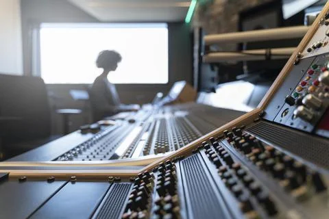 Control panel of a music recording studio with a woman in the background Stock Photos