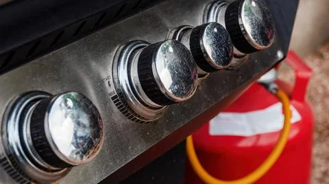 A control switch on a modern real use grill smoker with gas cylinder in the b Stock Photos