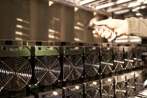 Controller in uniform scans ASIC bitcoin miners with barcode scanner in Stock-Fotos