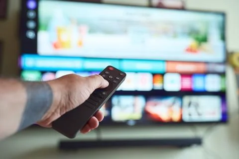 Controlling smart TV with remote. Stock Photos