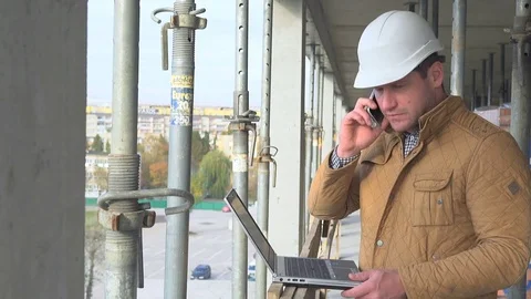 Contruction manager writing email on laptop answers phone call. Stock Footage 72360044