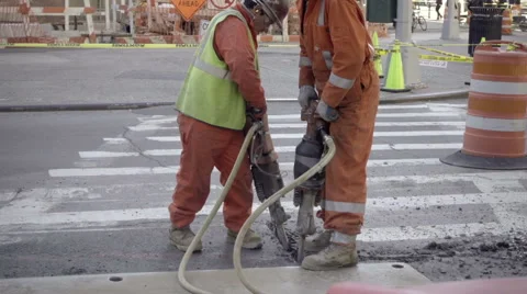 Contruction workers in orange suits and helmets drilling into the ground NYC 스톡 동영상 58759102