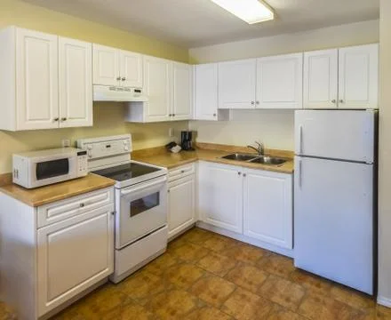 Conventional white kitchen with the table and chairs in dinner area. Stock-Fotos