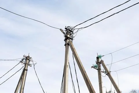 Converging utility poles form network, multiple leaning posts connected by cr 스톡 사진