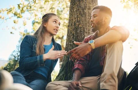 Conversation, argument and interracial couple in conflict in a park for Stock Photos