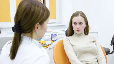 A conversation between a dentist and a patient by a young woman explaining the Stock Footage 134371821