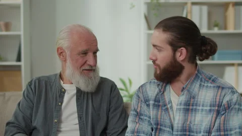 Conversation between generations young man and elder on the couch discuss life Stock Footage 263404794