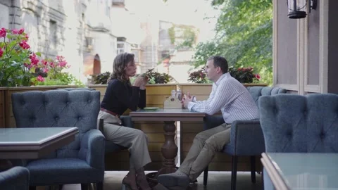 A conversation between a guy and a girl at a table in a cafe. Video stock 140952980