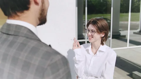 Conversation between two smoking professionals outside a modern office building Stock Footage 312902976