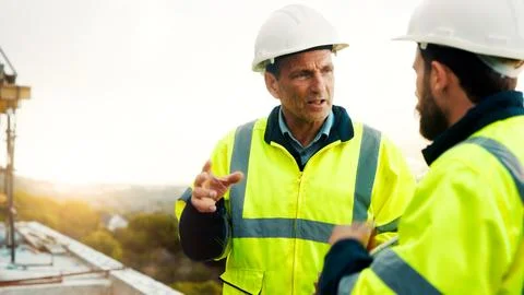 Conversation, engineering and men on construction site for building, planning or Stock Photos