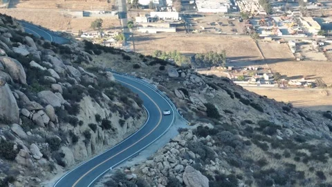 Convertible car drives down open winding road aerial drone Stock Footage 346752337