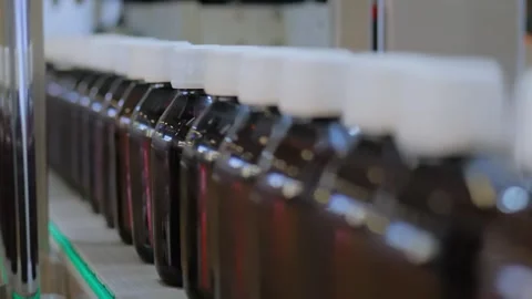 Conveyor belt of bottle labeling machine with empty glass bottles - close up Stock Footage 341853017