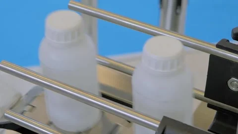 Conveyor belt of bottle labeling machine with empty white plastic bottles Stock Footage 344600913