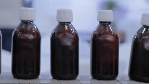 Conveyor belt of bottle labeling machine with empty amber glass bottles Stock Footage 344660686
