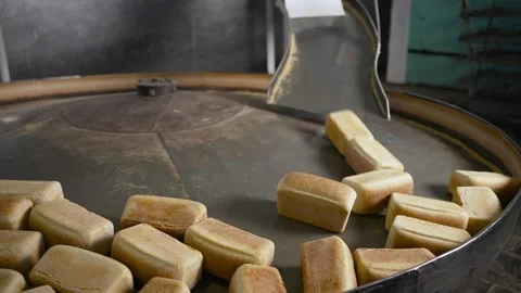 A conveyor belt is filled with bread and a few of them are being sliced Stock Footage 317455437