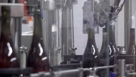 Conveyor with moving bottles filled with rose wine on which caps are screwed Stock Footage 230301034