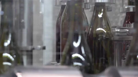 Conveyor with moving bottles into which wine is poured automatically close-up Stock Footage 230301378