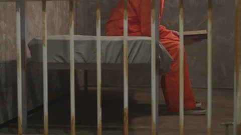 Convicted Criminal Sitting and Reading in a Jail Cell Stock Footage 208726933