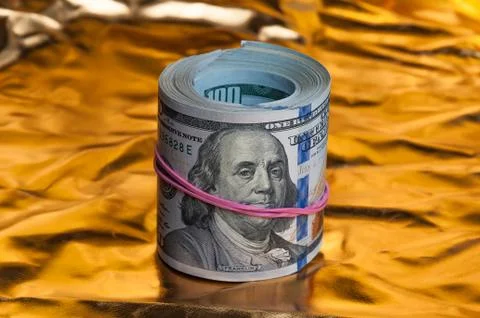 Convolving notes one hundred dollars on a bright gold background. Stock Photos