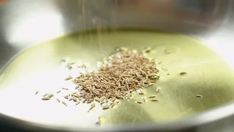 The cook adding cumin seeds into frying pan with olive oil. Stock Footage 194922407