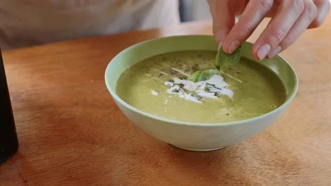 Cook adding a herbs and olive oil in green spinach puree soup at restaurant Stock Footage 100061253