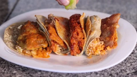 Cook adding lime juice to a plate of four different tacos Stock Footage 300931509