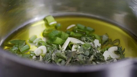 Cook adding salt into a pot with a garlicky oil sauce Stock Footage 84554710