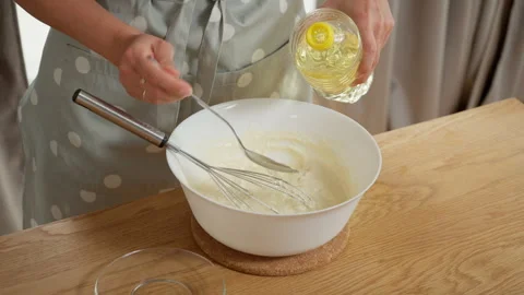 Cook adding a spoonful of vegetable oil to pancake batter and mixing it in Stock Footage 315904875