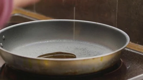 Cook adding two tablespoons of oil into a frying pan Stock Footage 84493993