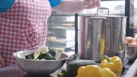 A cook is adding zucchini into a large pot Stock Footage 129993384