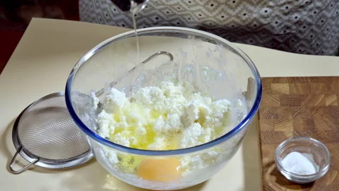 Cook adds egg to mixing bowl with sweet cookie dough ingredients. Slow motion. Stock Footage 299633448