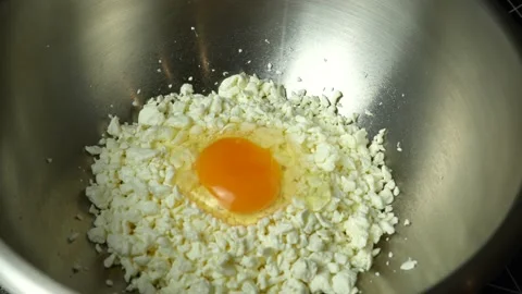 The cook adds a raw chicken egg to a bowl of homemade cottage cheese Stock Footage 231332839