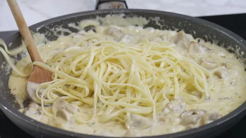 The cook adds the spaghetti to the pan with the black truffle sauce. Stock Footage 273238406